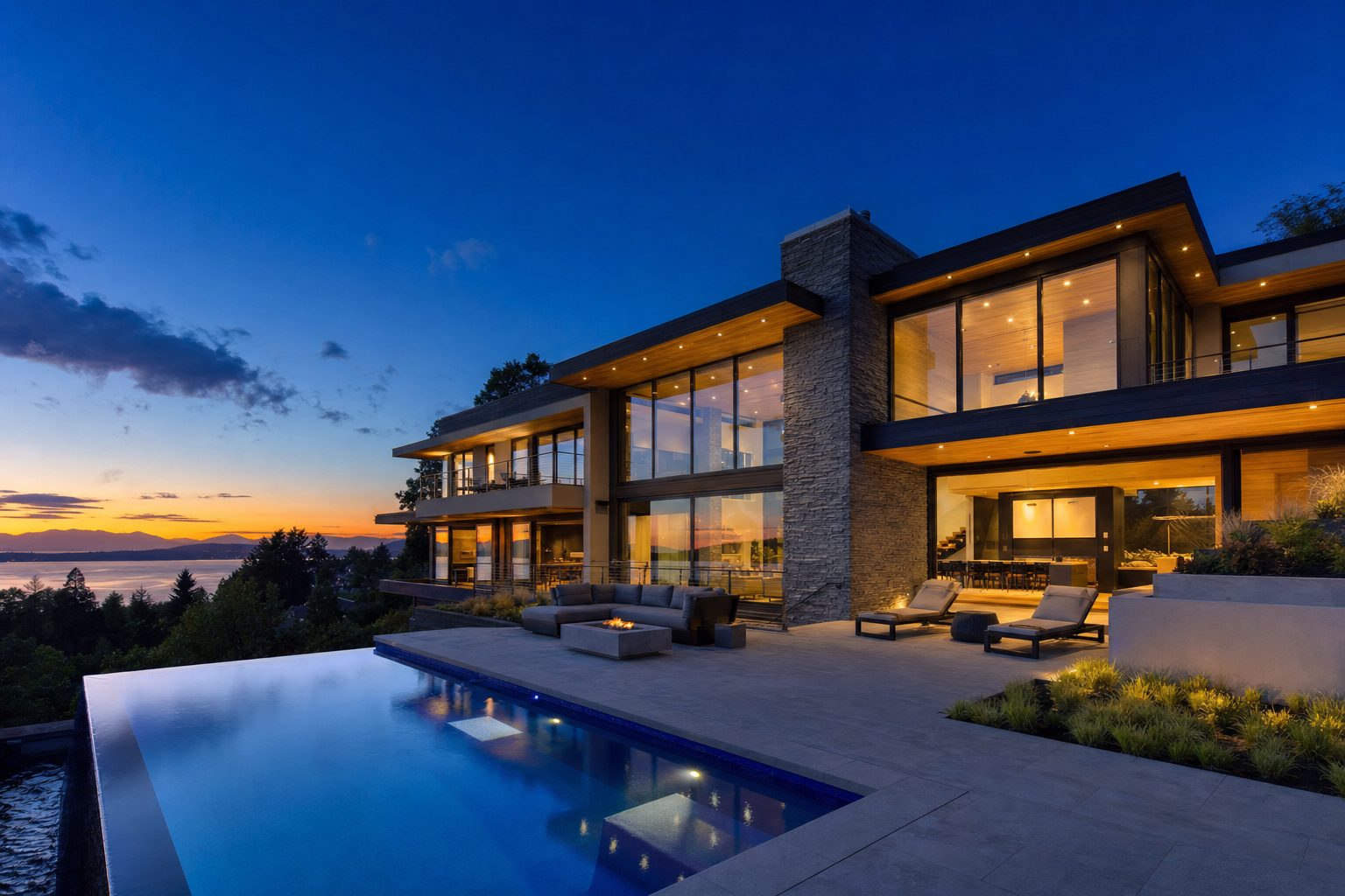 Modern luxury home at dusk with warm glowing interior lights